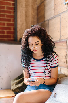 A young hispanic woman looking down at her phone in a cafe