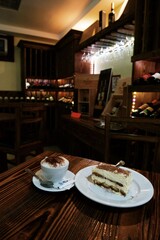 cup of cappuccino and tiramisu dessert on a wooden table in a cozy 