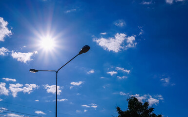 A light pole illuminates the exterior along the street against the fiery sun against the blue sky...