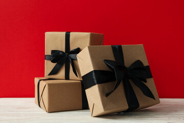 Gift boxes on wooden table against red background