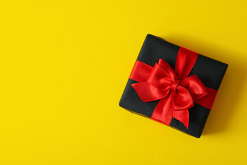 Gift box with red bow on yellow background
