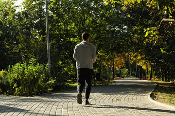 A man in a tracksuit running in the park in sunny morning