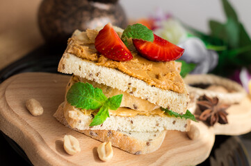 side view of peanut butter whole grain sandwich, toast with strawberries, healthy nutrition concept