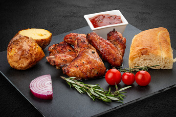 Grilled chicken wings with baked potatoes, matnakash and red sauce.Served on a stone plate