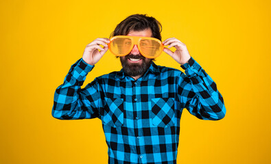 happy bearded guy wearing funny party glasses and checkered shirt on yellow background, lets celebrate