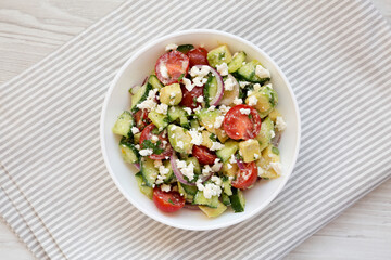Delicious Avocado Tomato and Cucumber Salad in a bowl on cloth, top view. Flat lay, overhead, from above.