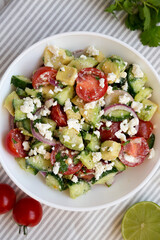 Delicious Avocado Tomato and Cucumber Salad in a bowl on cloth, top view. Flat lay, overhead, from above.