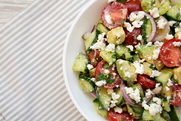 Delicious Avocado Tomato and Cucumber Salad in a bowl on cloth, top view. Flat lay, overhead, from above. Copy space.