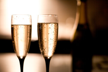 Two elegant champagne glasses on a dark surface on the kitchen warm light