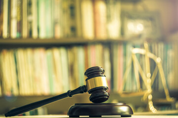 Wooden judge gavel with scales on library background
