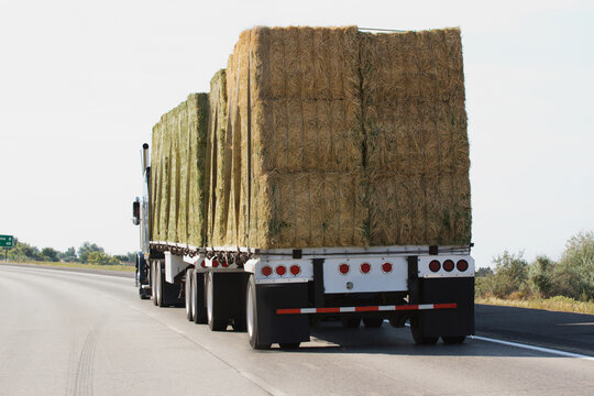 semi truck loaded with hay driving down freeway