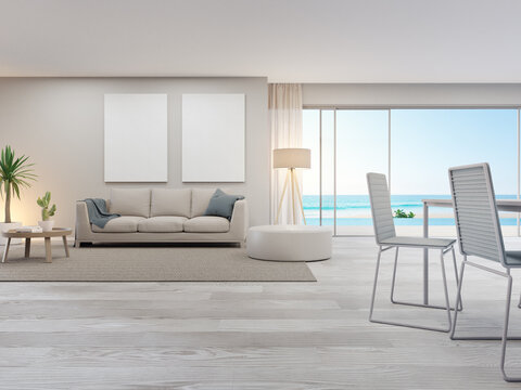 Blank picture frame near beige sofa on brown carpet of large living room in modern house or luxury pool villa. Cozy home interior 3d rendering with beach and sea view.