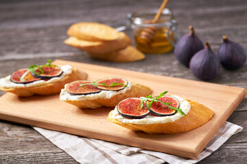 Bruschetta with ricotta cheese, ripe figs and honey  on a rustic table.