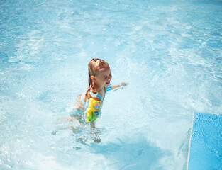 Fototapeta na wymiar little girl swims in the pool in the outdoor water park
