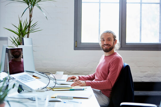 Smiling Businessman Using Computer In Creative Office