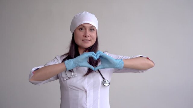 Female doctor with surgeon cap and heart shaped hands. White background and copy space. Medium shot.