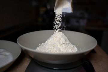 Pouring flour into a deep plate. Close-up.