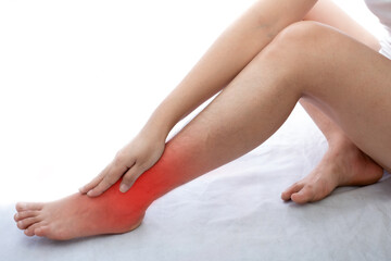 Young woman with ankle pain at white background