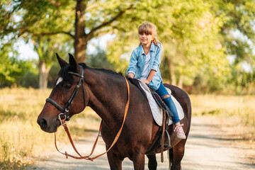 Obraz premium Cute little girl with long hair riding a horse outdoors. Pet therapy