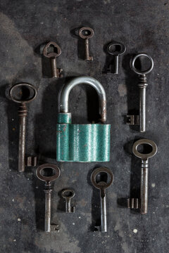 Keys around a padlock on dark metal background