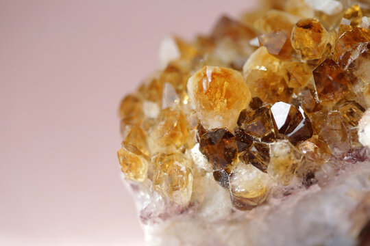 Close Up Of A Yellow Citrine Crystal Against A Pink Background