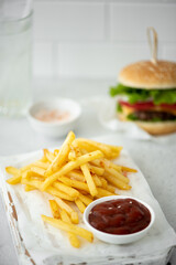 fries with ketchup and hamburger on white table