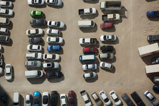 Aerial view of many cars parked in a parking lot outside. - Powered by Adobe