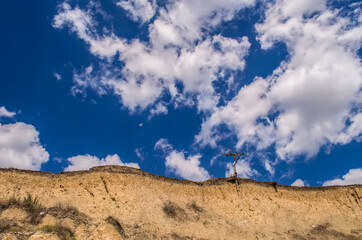 Blue sky with white clouds and sandy slope.