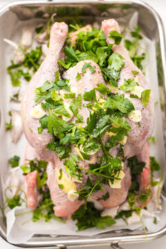 overhead view of a raw chicken prepared for roasting, with lemon