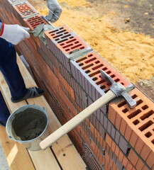 The worker lays bricks on the wall of the house.
