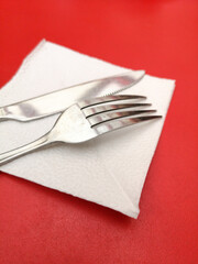 Knife and fork in a white napkin on a red