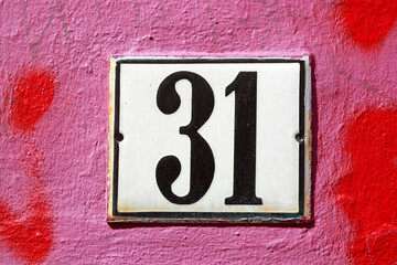 Weisses Hausnummernschild Nr. 31 auf rot bemalter Hauswand, Deutschland, Europa