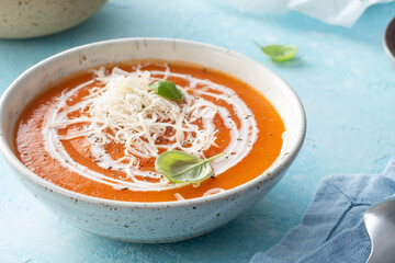 Pumpkin and carrot soup with cream on blue stone background.