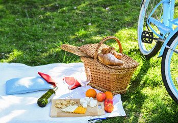 picnic basket with food on blanket. spring eating outdoor. family day. all goods for picnic. love date. vintage bicycle on green grass. green summer park food. having tasty lunch. time for dinner
