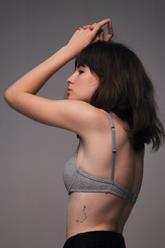 Young girl in grey bra with constellation tattoo on back