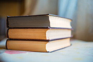 Three vintage books are stacked on the table indoors.