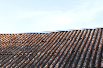 Old dirty gray slate roof against blue sky