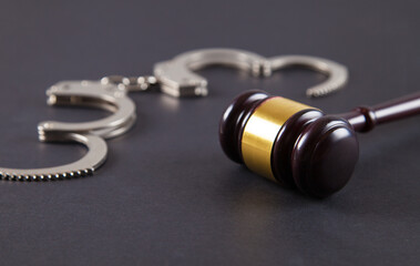 Police handcuffs and judge gavel on an isolated black background.
