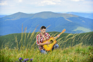 Inspired musician play rock ballad. Compose melody. Inspiring environment. Acoustic music. Summer music festival outdoors. Playing music. Sound of freedom. Man with guitar on top of mountain