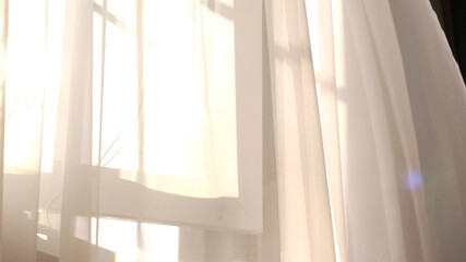 wind blows through the open window in the room. Waving white tulle near the window. Morning sun...