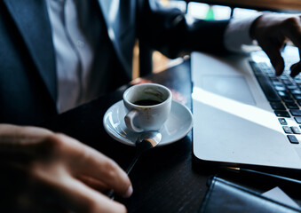 business man in a cafe at the table in front of a laptop work a cup of coffee at the table communication technology