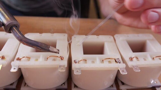 Hand soldering the terminals of a transformer electronic component - close up