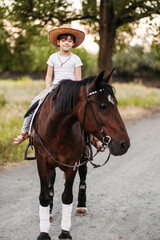 Boy with hat riding a horse outdoors. Pet therapy