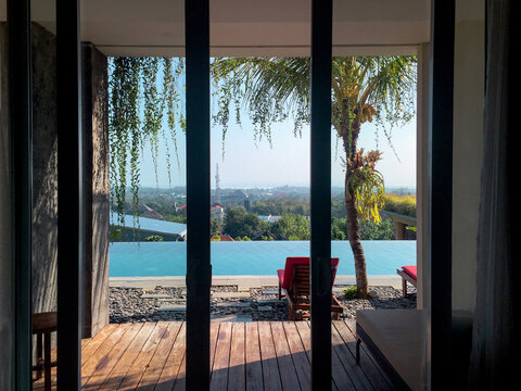 Windows views of a infinite pool and city from inside of a house