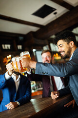 People, friendship and celebration concept. Happy business male friends drinking beer at pub