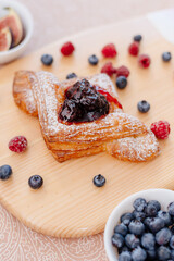Puff pastry bun with currant jam and powdered sugar. Breakfast with puff berries and coffee. In the background berries and turk for coffee