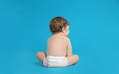 Cute little baby in diaper on light blue background. Space for text