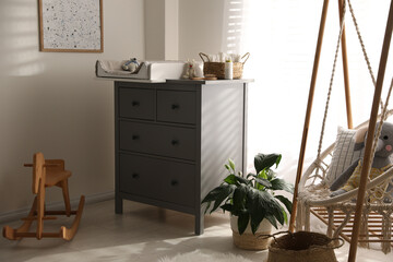 Baby room interior with modern changing table and wooden swing