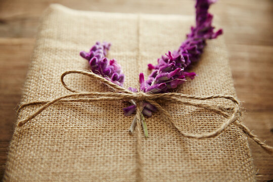 Still life of burlap wrapped present with purple flower