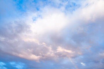 A shy rainbow breaks through a cluster of clouds after a rainy day